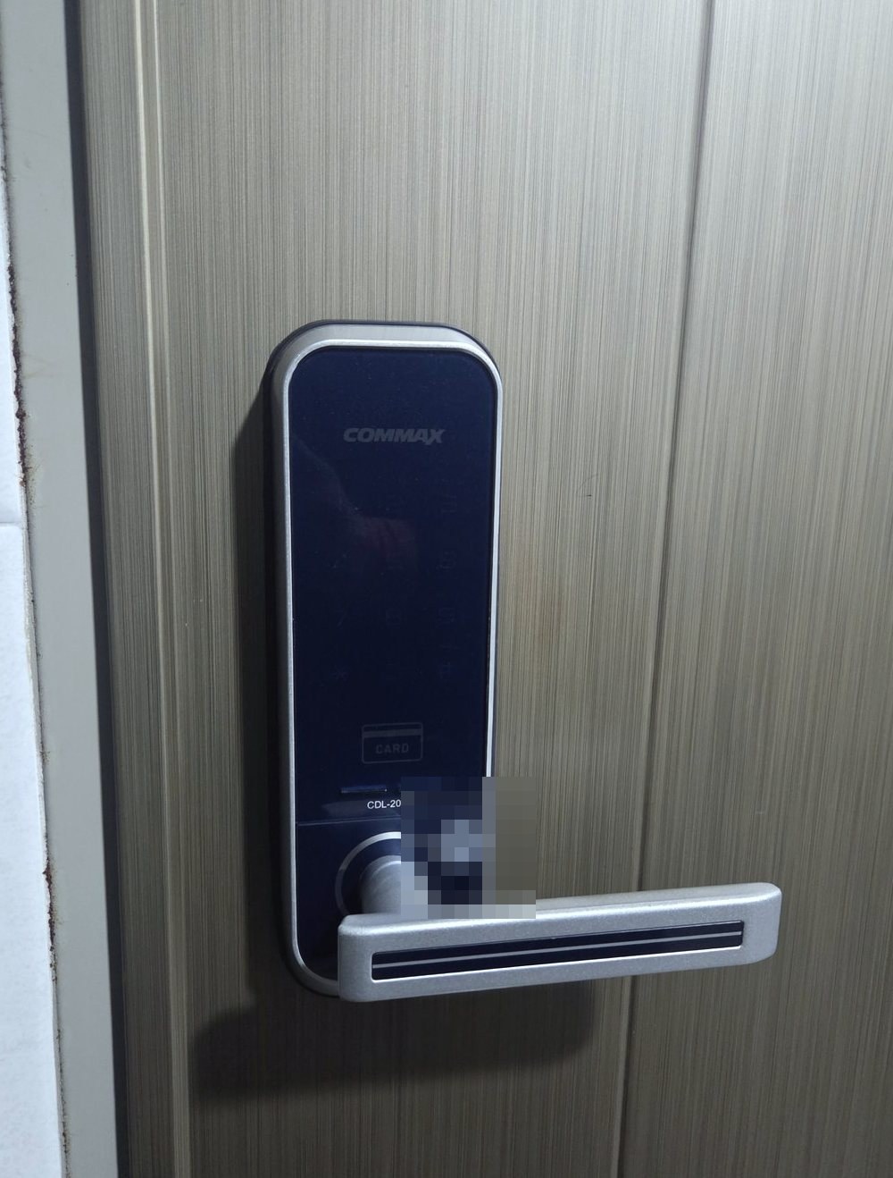 계양구 계양3동 출장 — 회갈색 결무늬 문에 달린 남색 유리판 레버형 도어락, 은색 테와 카드 표시, 레버 손잡이의 스티커는 가림